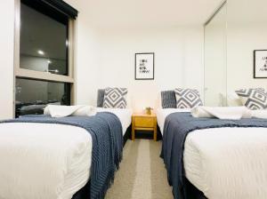 een kamer met 3 bedden en blauwe en witte dekens bij Mega Style Apartments Kings Domain in Melbourne