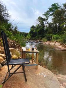 una silla y una mesa junto a un río en Nhà nghỉ đèo Tà Pứa 