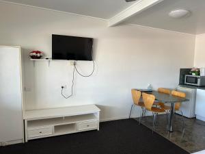Zimmer mit einem Tisch und einem TV an der Wand in der Unterkunft Shell Motel (Pearly Shell Motel) in Bowen