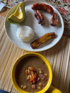 einen Teller mit Essen mit einer Schüssel Suppe und Fleisch in der Unterkunft Glamping Orosierra in Chinchiná