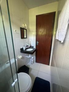 La salle de bains est pourvue de toilettes et d'une porte en bois. dans l'établissement hospedagemsaopedro apartamento com garagem a 13 km de Cabo frio 22 km de arraial do cabo, à São Pedro da Aldeia