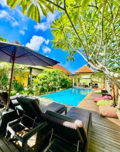 uma piscina com cadeiras e um guarda-sol ao lado de uma casa em Dream Beach Hostel Lembongan em Nusa Lembongan