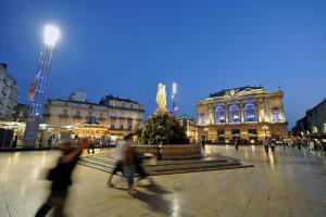 un grupo de personas caminando por una plaza con una estatua en Villa Bellagio Euromedecine by Popinns, en Montpellier