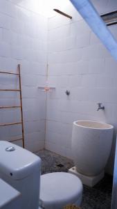 La salle de bains blanche est pourvue de toilettes et d'un lavabo. dans l'établissement Moyo Island Resort, à Moyo Island