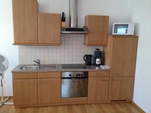 een keuken met houten kasten, een wastafel en een magnetron bij Winzerhof Klua Hoada in Illmitz