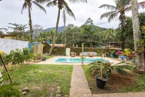 a backyard with a swimming pool and palm trees at SURFSIDE MARESIAS in São Sebastião