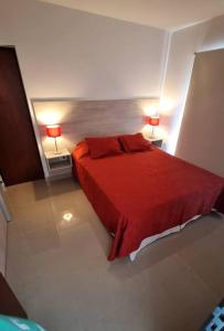 a bedroom with a red bed with two lamps at Apart dos ambientes - Macrocentro Salta in Salta +12 photos
