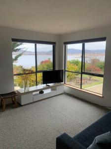 a living room with a tv and two large windows at Apartment minutes to Lake in Jindabyne