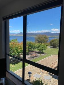 a window with a view of the water seen through it at Apartment minutes to Lake in Jindabyne