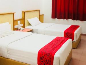 a room with two beds with red and white sheets at Intan Beach Resort in Kuala Terengganu