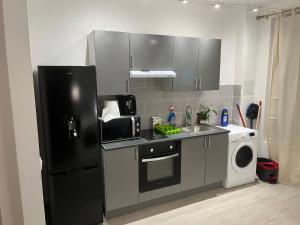 a kitchen with a black refrigerator and a sink at Logement complet à proximité de Paris in Le Blanc-Mesnil