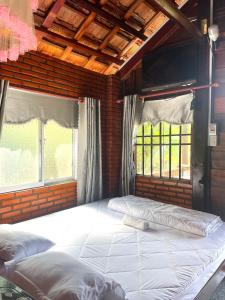a large bed in a room with two windows at Du Nam Riverside Tour Trọn Gói in Tân Phú