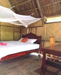 ein Schlafzimmer mit einem Himmelbett und einem Tisch in der Unterkunft Du Nam Riverside Tour Trọn Gói in Tân Phú