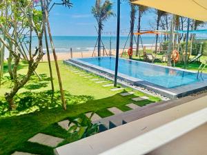 a swimming pool with the beach in the background at Whispering waves beachfront villa in Tiến Thành