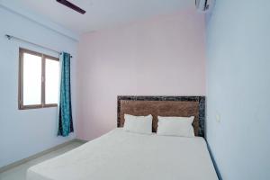 a bedroom with a white bed with a window at OYO SM GALAXY in Kānpur