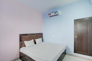 a bedroom with a white bed with a wooden door at OYO SM GALAXY in Kānpur