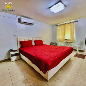 a bedroom with a bed with red sheets and a window at Magic Garden Residence Bangkok in Bangkok
