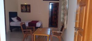 AthmA ArunA - Homestay Tiruvannamalai في تيروفانمالي: غرفة مع طاولة وكراسي وسرير