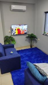 uma sala de estar com um sofá azul e uma televisão de ecrã plano em MEDPY HOSTEL em Pedro Juan Caballero
