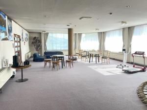 a large room with tables and chairs and windows at Felse Inn Gakusui in Hakuba