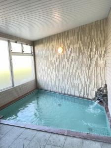 a large swimming pool in a room with a window at Felse Inn Gakusui in Hakuba