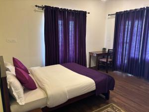 a bedroom with a bed with purple curtains and a table at Casa Felicia-Adding happy moments to your diary in Ooty