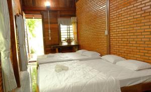 2 Betten in einem Zimmer mit Ziegelwand in der Unterkunft Du Nam Riverside Tour Trọn Gói in Tân Phú