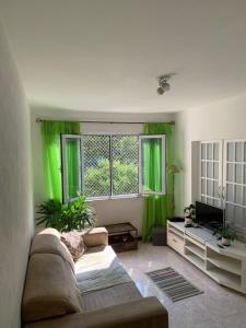 uma sala de estar com cortinas verdes e um sofá em Apartamento Aconchegante na Zona Sul, Botafogo Rj no Rio de Janeiro