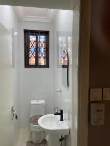 a white bathroom with a toilet and a sink at Luxury Townhome in Oyarifa in Oyarifa