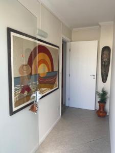a hallway with a painting on the wall and a door at Lar doce lar da Lu in Curitiba