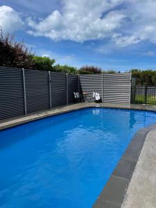 une grande piscine bleue avec une clôture dans l'établissement Kingsdown Manor B&B Timaru, à Timaru