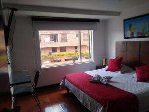a bedroom with a bed with a red blanket and a window at Hotel Bogotá Real DC in Bogotá