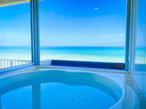 a bath tub in a room with a view of the ocean at Seven Colors Ishigakijima in Ishigaki Island