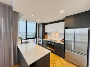 a kitchen with stainless steel appliances and a large window at Harbour Towers, Newcastle's Luxe Apartment Stays in Newcastle