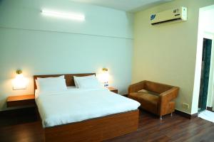 sypialnia z dużym łóżkiem i krzesłem w obiekcie Andheri Sports Complex - VIP Guest House w Bombaju