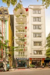 a tall white building with balconies on a street at The Oversleep Catba Hostel in Cat Ba