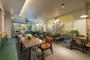 a restaurant with tables and chairs and a mural at The Oversleep Catba Hostel in Cat Ba
