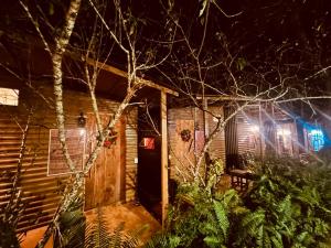Cabaña de madera con puerta de madera por la noche en Chino Homestay Măng Đen en Kon Tum