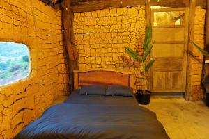 um quarto com uma cama numa parede de tijolos em Mơ Niê Farmstay & Cafe em Kon Von Kla