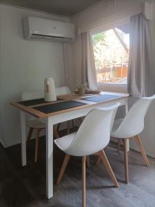 un tavolo da pranzo con 2 sedie bianche e una finestra di Tinyhaus idyllisch am Waldesrand a Cottbus