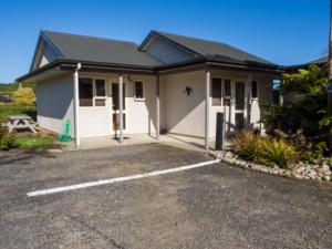 Karamea的住宿－Karamea River Motels，一座白色的小房子,设有停车场