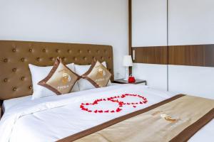 Una cama con una colcha blanca con flores rojas. en Phong Lan Apartments en Hai Phong