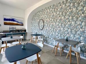a restaurant with tables and white chairs and a wall at TaliaKà B & B in Lipari