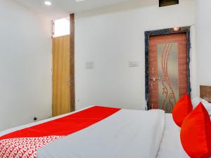 a bedroom with a bed with red pillows and a door at OYO Hotel Shivansh in Bhopal
