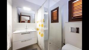 a white bathroom with a sink and a shower at Villa Milonga - beautiful villa with pool near the beach in Jan Thiel +15 photos
