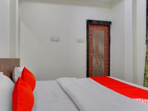 a bedroom with a bed with red pillows and a door at OYO Hotel Shivansh in Bhopal