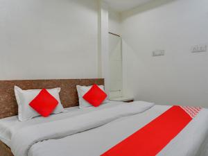 1 dormitorio con 2 camas y almohadas rojas y blancas en OYO Hotel Shivansh en Bhopal