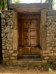 una antigua puerta de madera en una pared de piedra en TRANQUIL Tropical Hideaway en Kaduwela