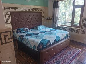 um quarto com uma cama com uma colcha em Wanderers Homestay -All mountain facing rooms em Kalpa