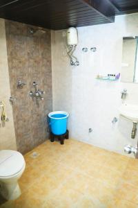 a bathroom with a toilet and a blue bucket at Andheri Sports Complex - VIP Guest House in Mumbai